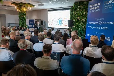 A full room of attendees seen from the back during the opening session of Business Wallets in Action in Utrecht, with the organisers' slide on screen.