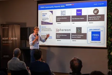 A speaker presenting the FIDES Community Awards 2026 slide showing the Best Business Wallet finalists, including the Credenco Business Wallet.